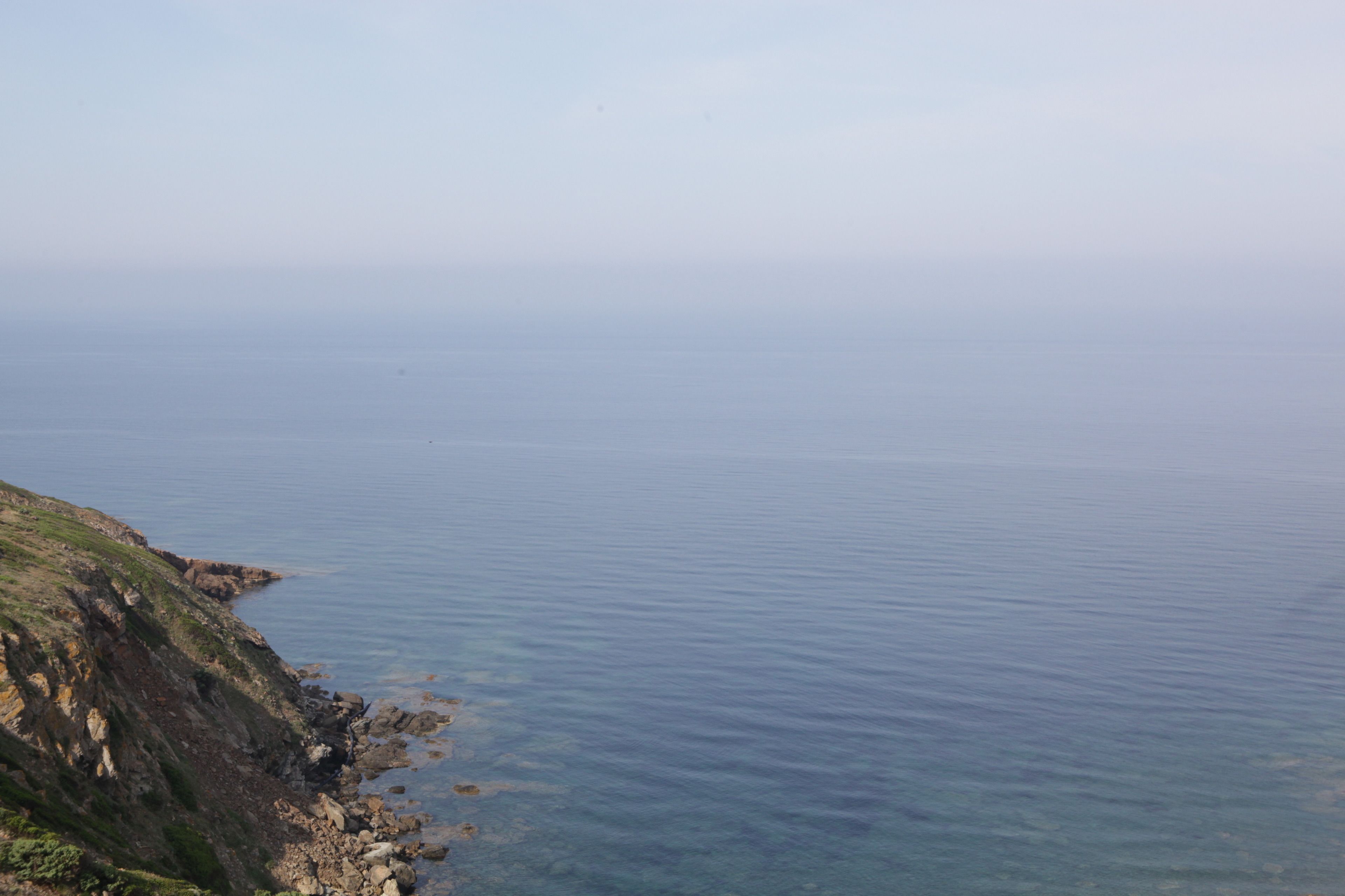 Eine Küstenlandschaft mit felsiger Küste und ruhiger See.