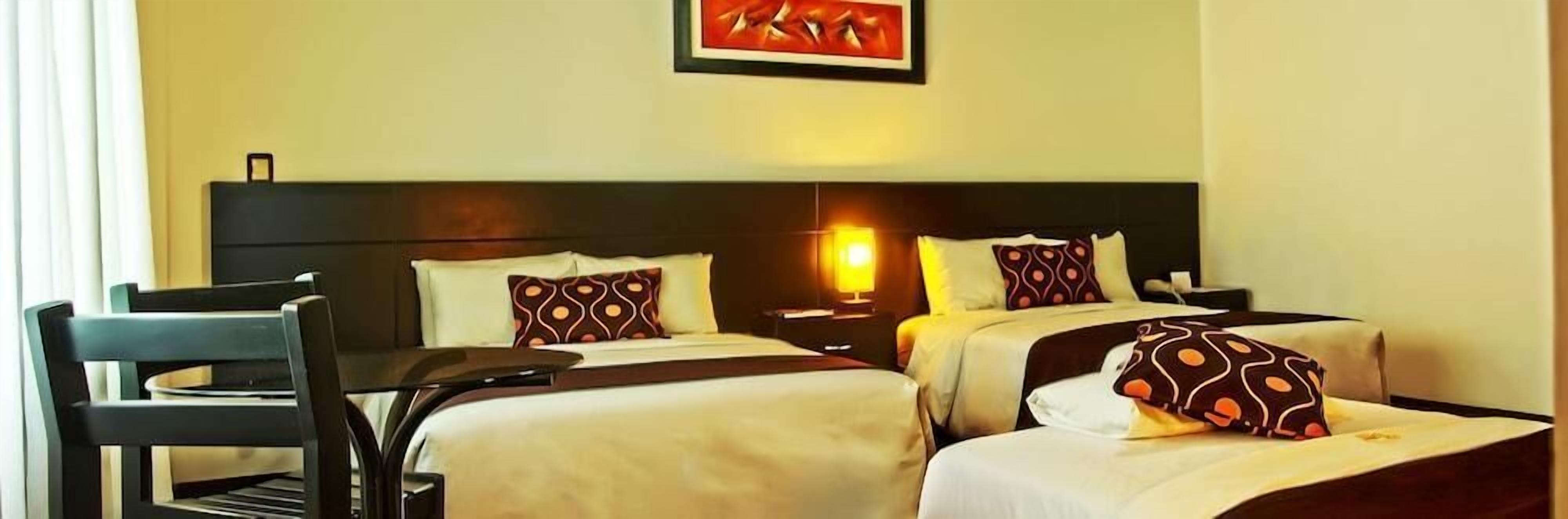 A hotel room with two beds, a desk, and a chair.