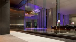Um hall moderno com divisória de vidro, balcão de recepção e um candelabro.