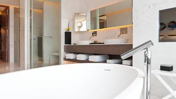 A modern bathroom with a large white bathtub, a glass-enclosed shower, and a wooden vanity with a large mirror.