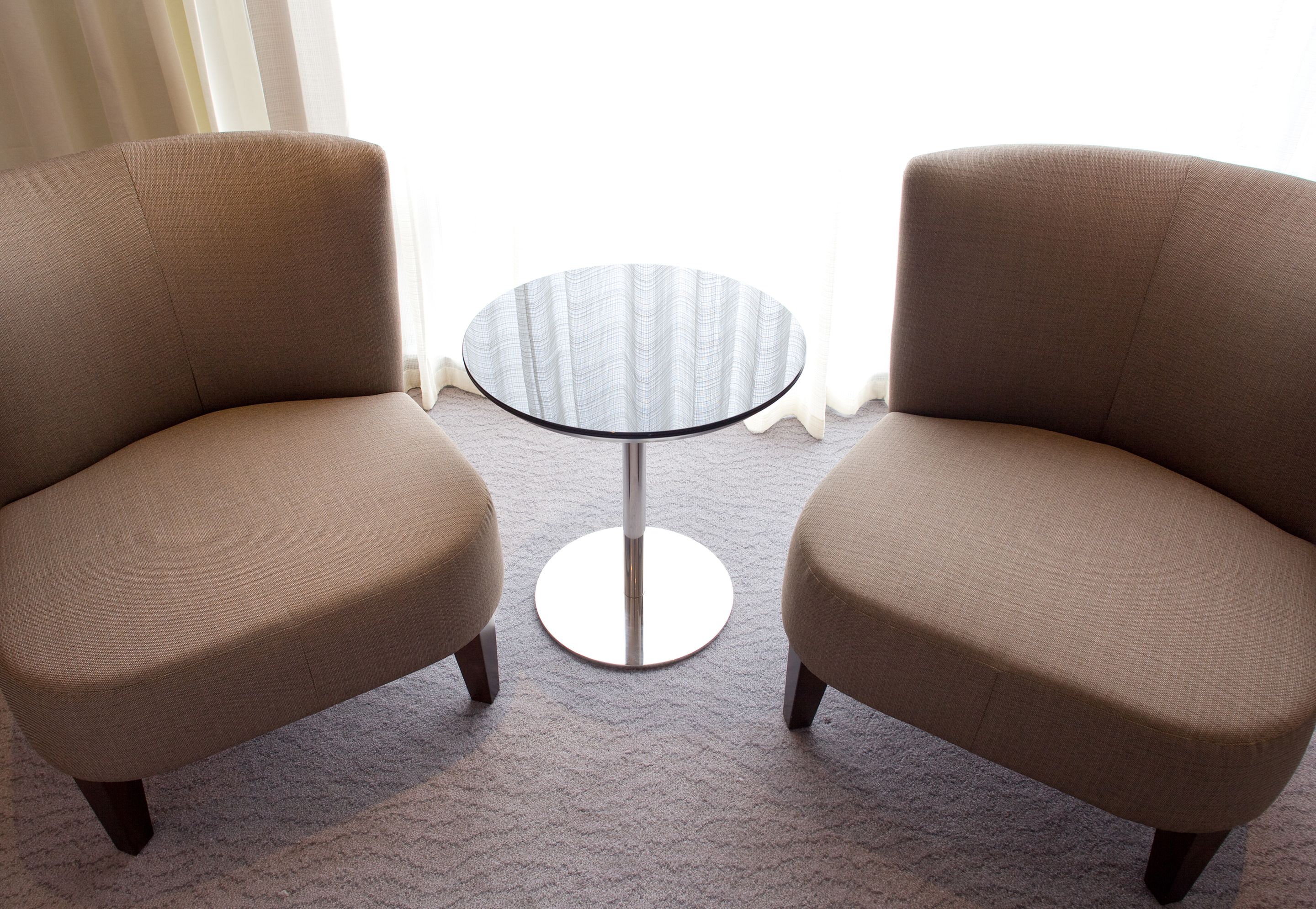 Twee fauteuils tegenover elkaar met een kleine ronde tafel ertussen.