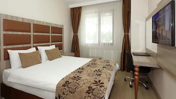 Una habitación de hotel con una cama grande, un escritorio y un televisor.