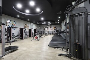 A gym with treadmills, weight machines, and a mirrored wall.
