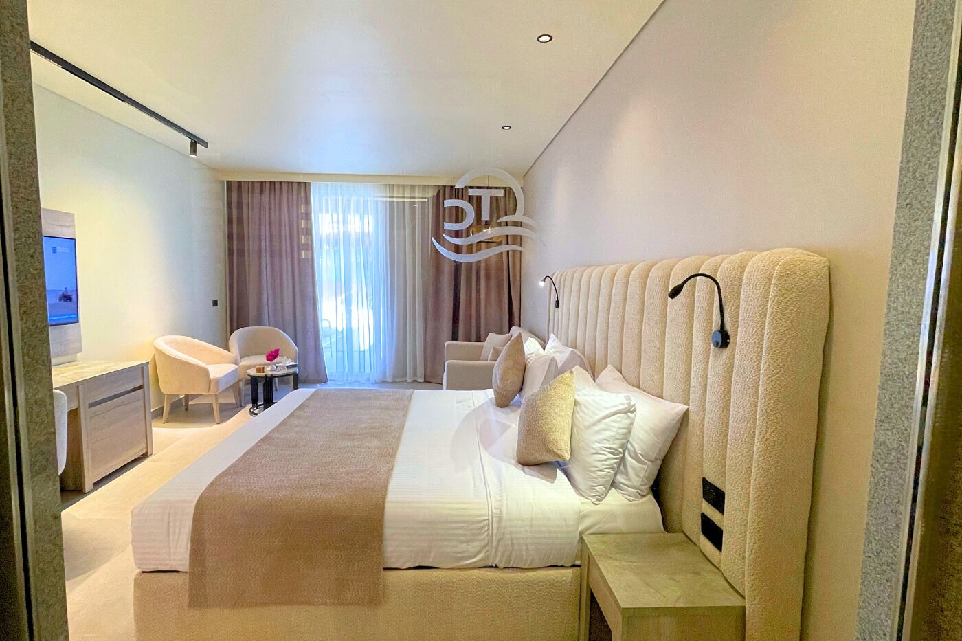 A hotel room with a large bed, bedside tables, a desk, and a chair.
