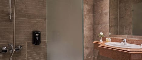 A modern bathroom with a glass-enclosed shower, a sink with a marble countertop, and a large mirror.
