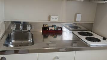 A kitchen with a stainless steel sink, two ovens, a microwave, and white cabinets.