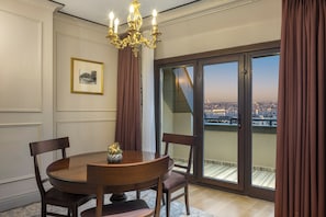 A dining room with a round table, chairs, a chandelier, a framed picture, and a view through large sliding doors. - Palazzo Donizetti Istanbul, Tapestry Collection by Hilton (Istanbul)