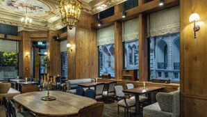 A restaurant with wooden walls, chandeliers, and large windows with views of buildings. - Palazzo Donizetti Istanbul, Tapestry Collection by Hilton (Istanbul)