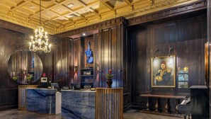 A lobby with a marble reception desk, a grand chandelier, a piano, and a framed portrait on the wall. - Palazzo Donizetti Istanbul, Tapestry Collection by Hilton (Istanbul)