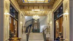 A grand lobby with a high ceiling, a staircase, and a chandelier. - Palazzo Donizetti Istanbul, Tapestry Collection by Hilton (Istanbul)