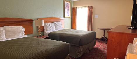 Habitación de hotel con dos camas, un escritorio, un televisor y una ventana con cortinas.