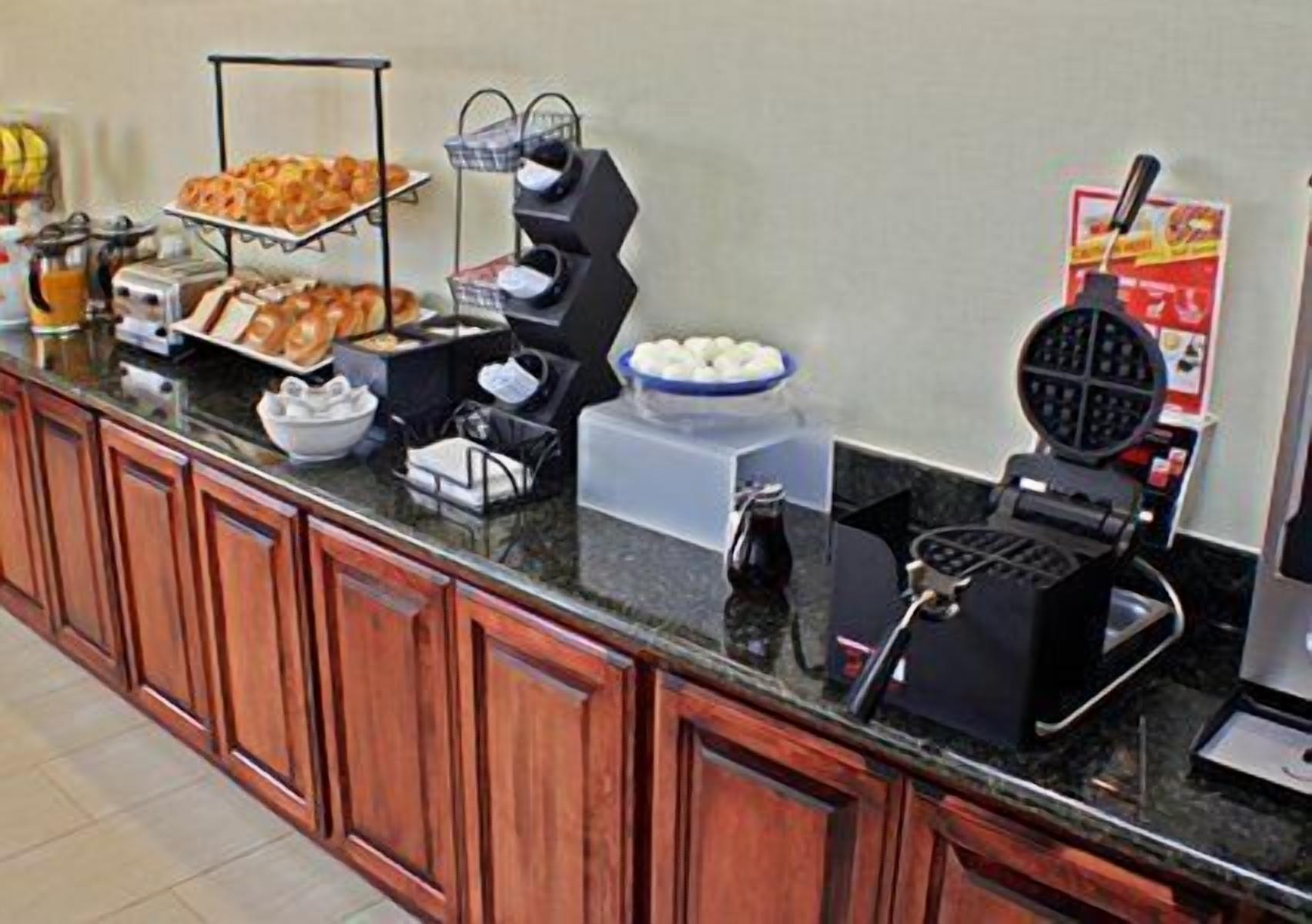 A breakfast bar with various food items and a waffle maker.