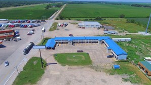 Vista aérea de una extensa zona industrial con un edificio central de techo azul, rodeado de estacionamientos y campos.