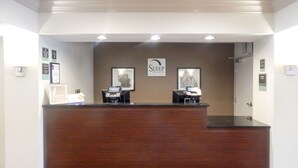 A reception desk with two computer stations, framed pictures on the wall, and a sign that reads "Sleep Inn & Suites." - Sleep Inn & Suites Evergreen I-65 (Evergreen)