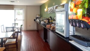 A breakfast bar with a coffee machine, a refrigerator, and a juice dispenser. There are chairs and a table with a view of the outdoors. - Sleep Inn & Suites Evergreen I-65 (Evergreen)