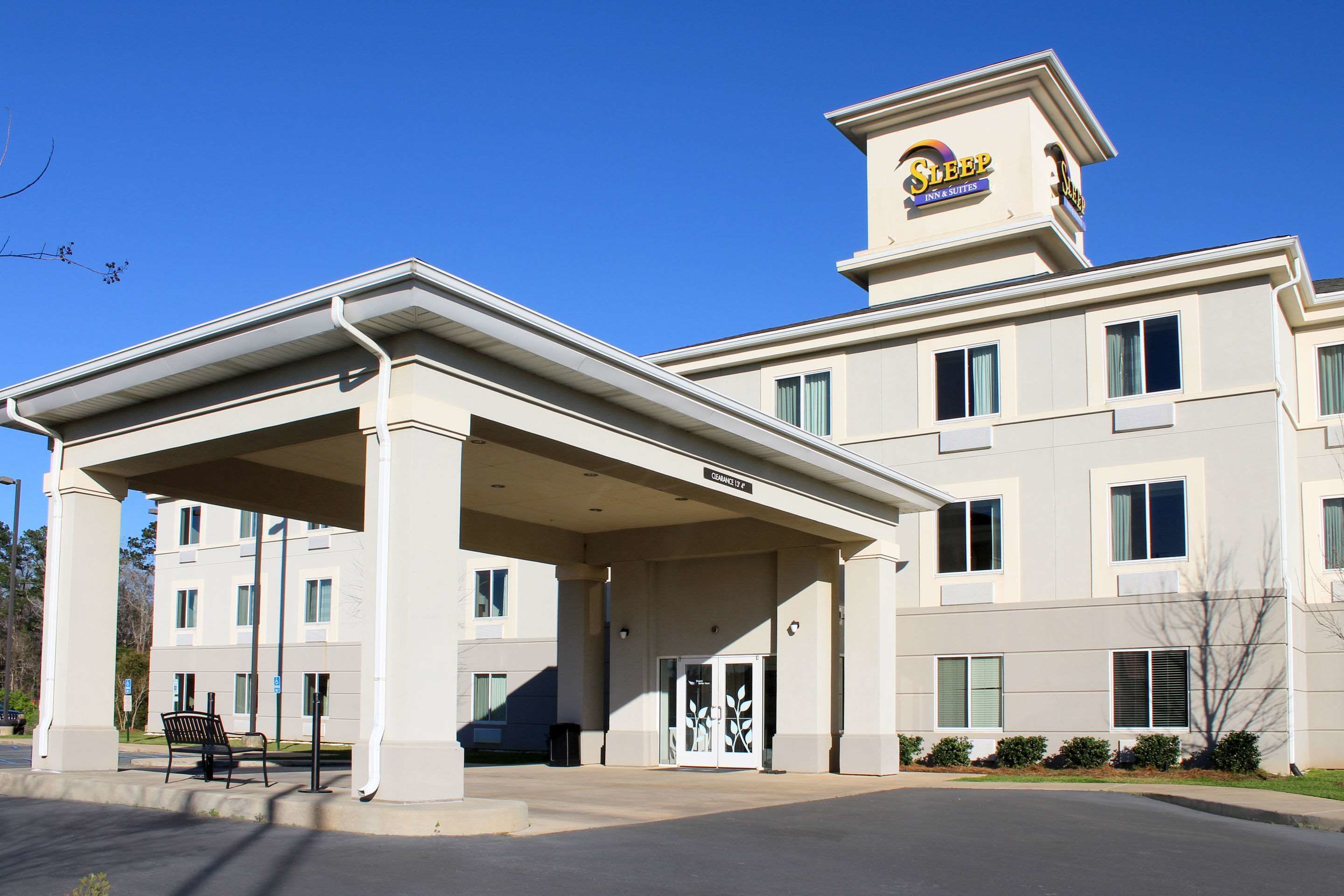 A hotel with a covered entrance, multiple windows, and a sign indicating it is a Sleep Inn & Suites.