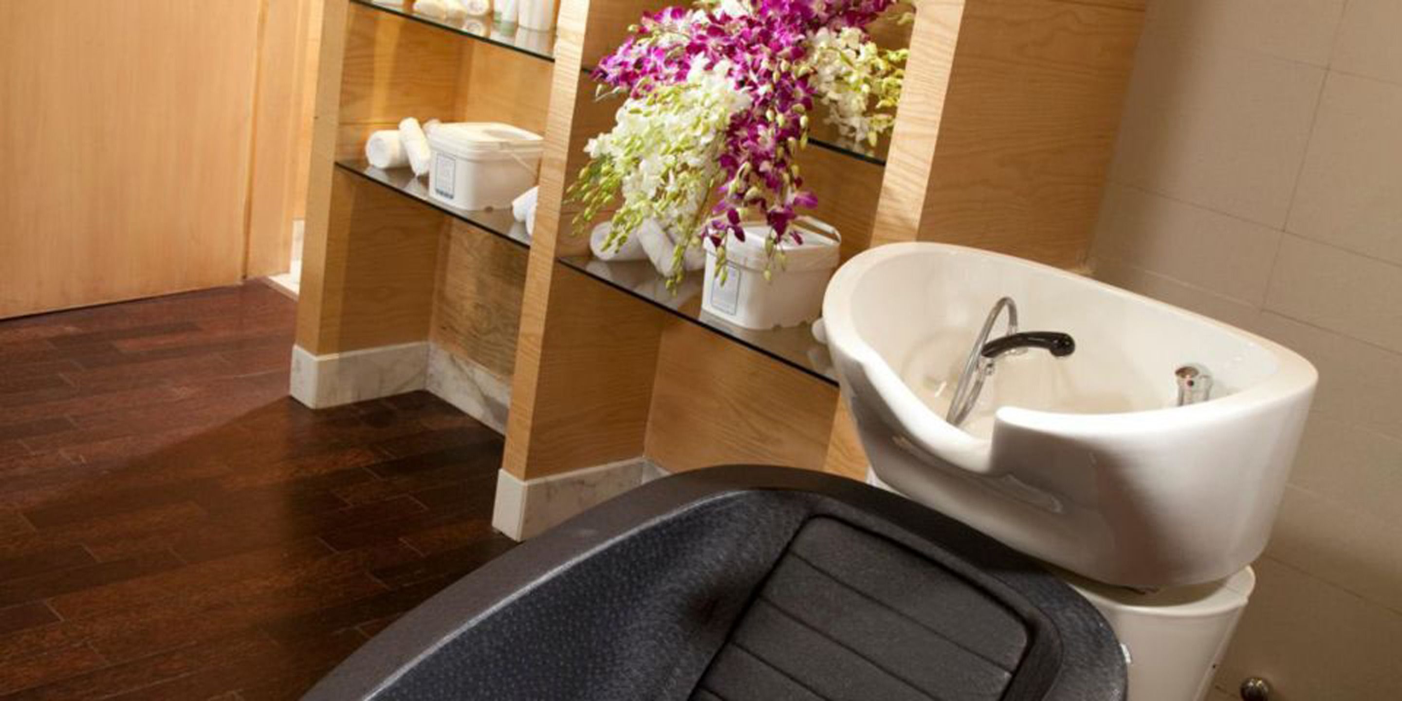 A bathroom with a freestanding bathtub, a glass shelf with toiletries, and a mirror.
