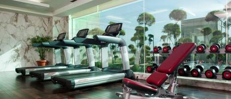 A gym with treadmills, a bench press, and dumbbells.