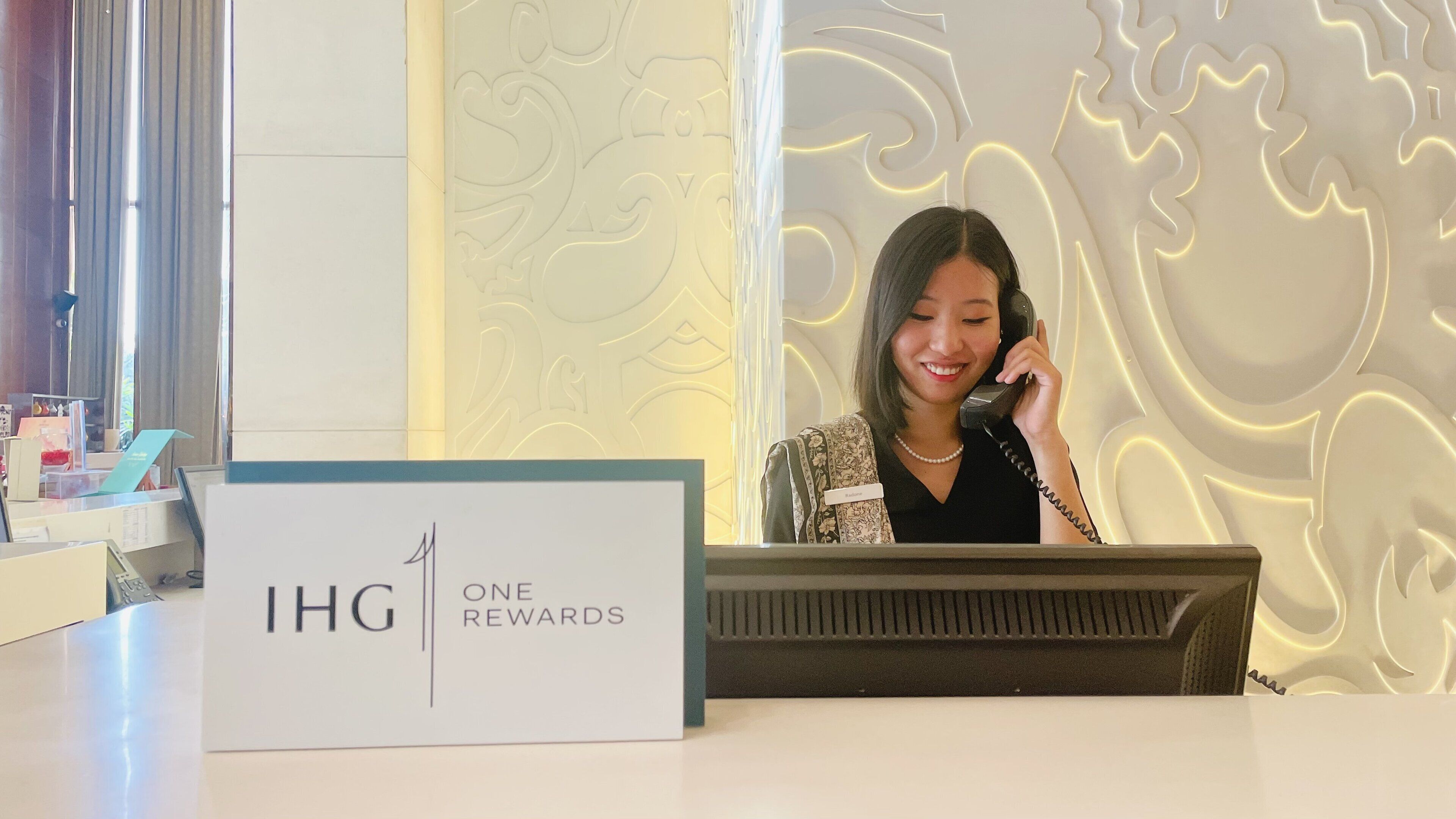 Een receptiebalie met een bord waarop 'IHG ONE REWARDS' staat.