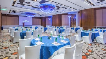 A conference room with round tables, white chairs, and blue tablecloths.