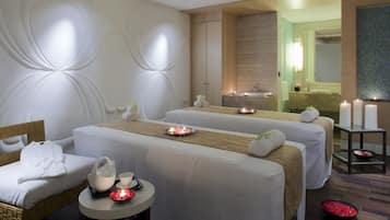 Relax in a serene spa room with two massage tables, a tea service area, and a calming atmosphere.