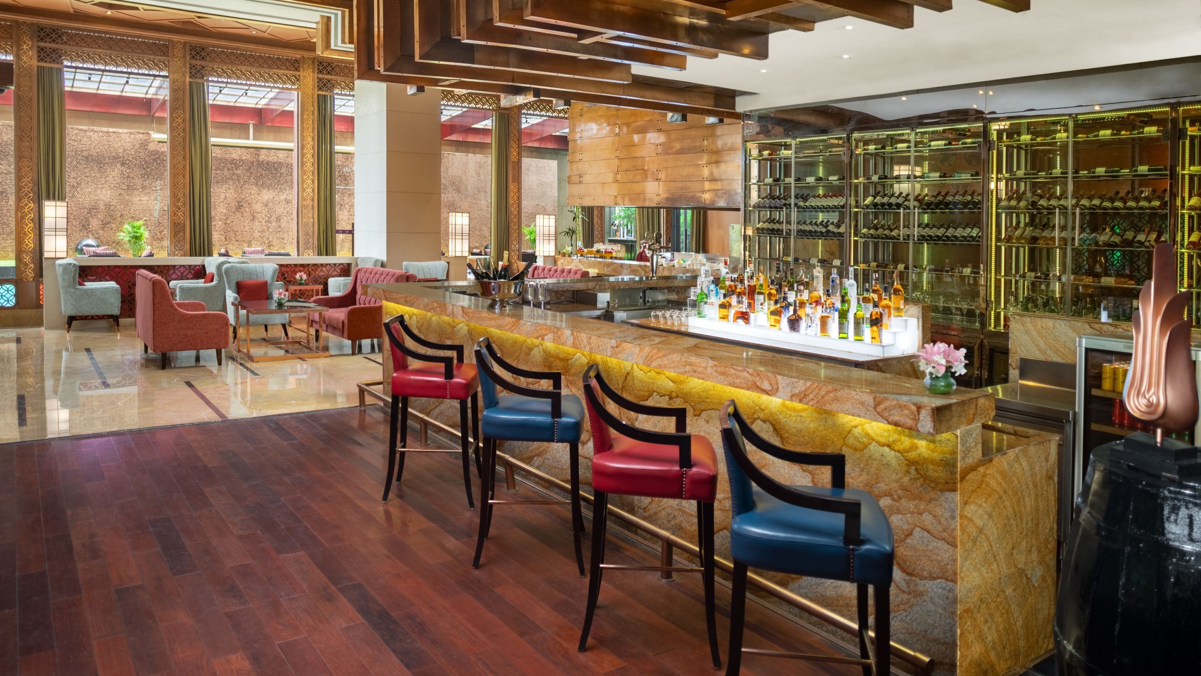 A bar area with a marble countertop, multiple bar stools, and a wine display.