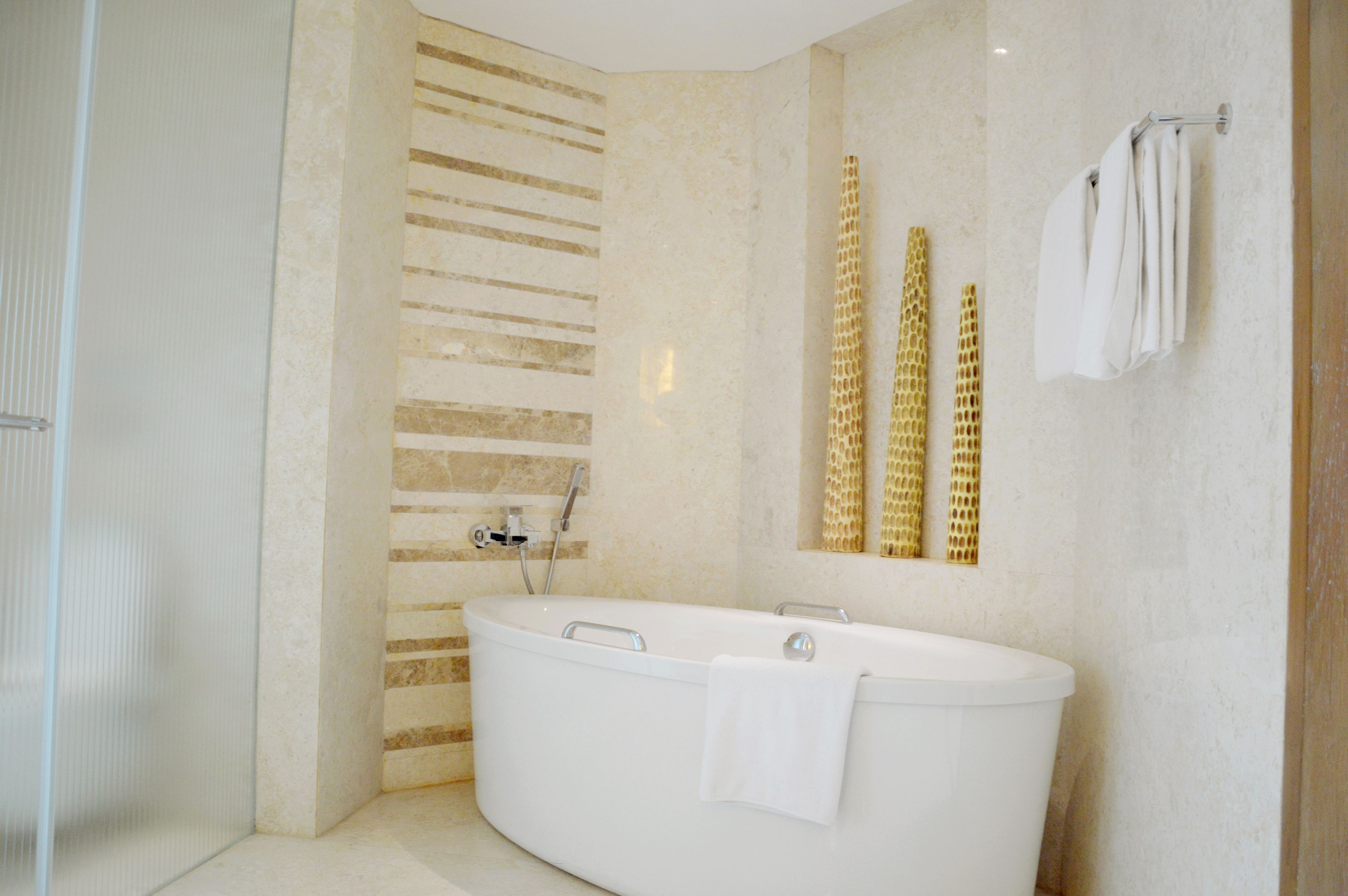 A modern bathroom with a freestanding bathtub, a shower area, and a large mirror with gold decorative elements.
