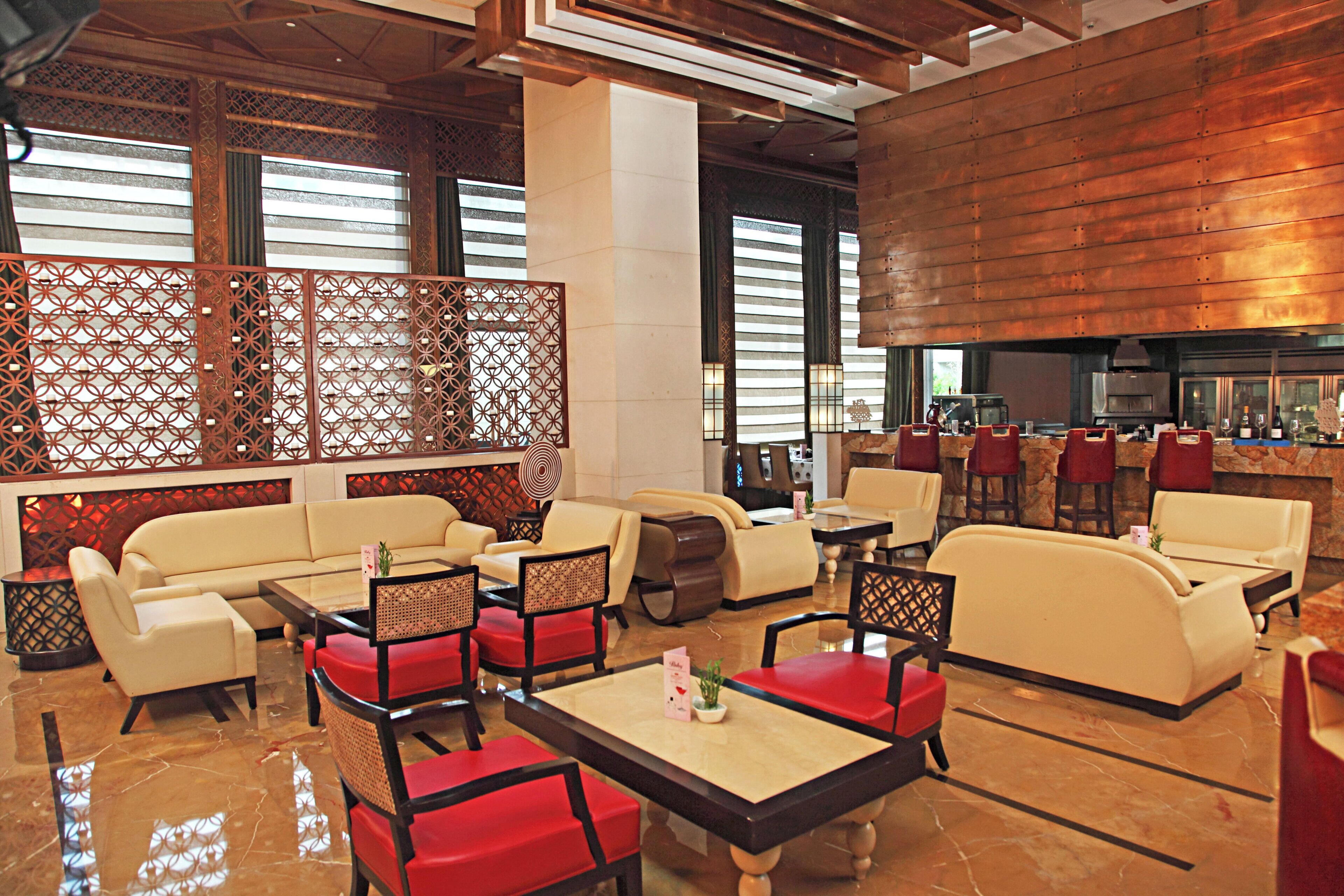 A modern hotel lobby with seating areas, a bar, and a fireplace.