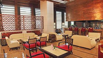 A modern hotel lobby with seating areas, a bar, and a fireplace.