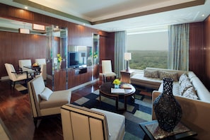 Habitación de hotel con sofá, sillas, televisión y vistas al paisaje.