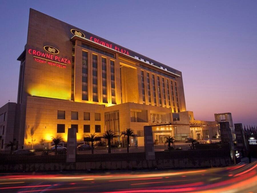 A modern hotel with a prominent sign reading 'CROWNE PLAZA TODAY NEW DELHI.'