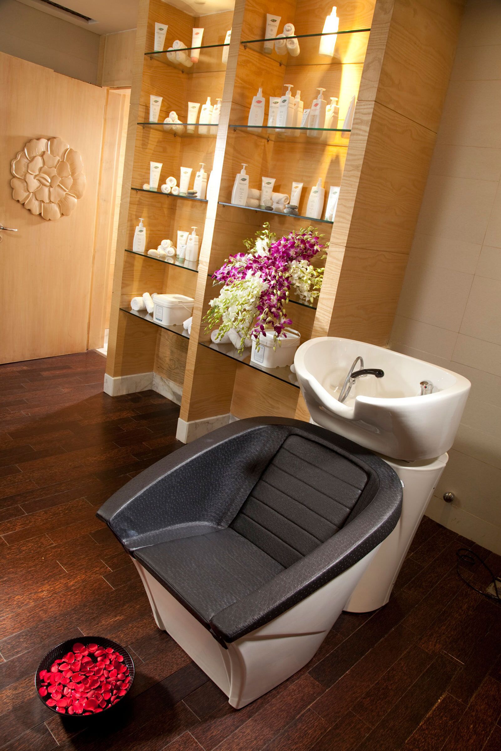 A bathroom with a black bathtub, a white sink, and a shelf with toiletries.