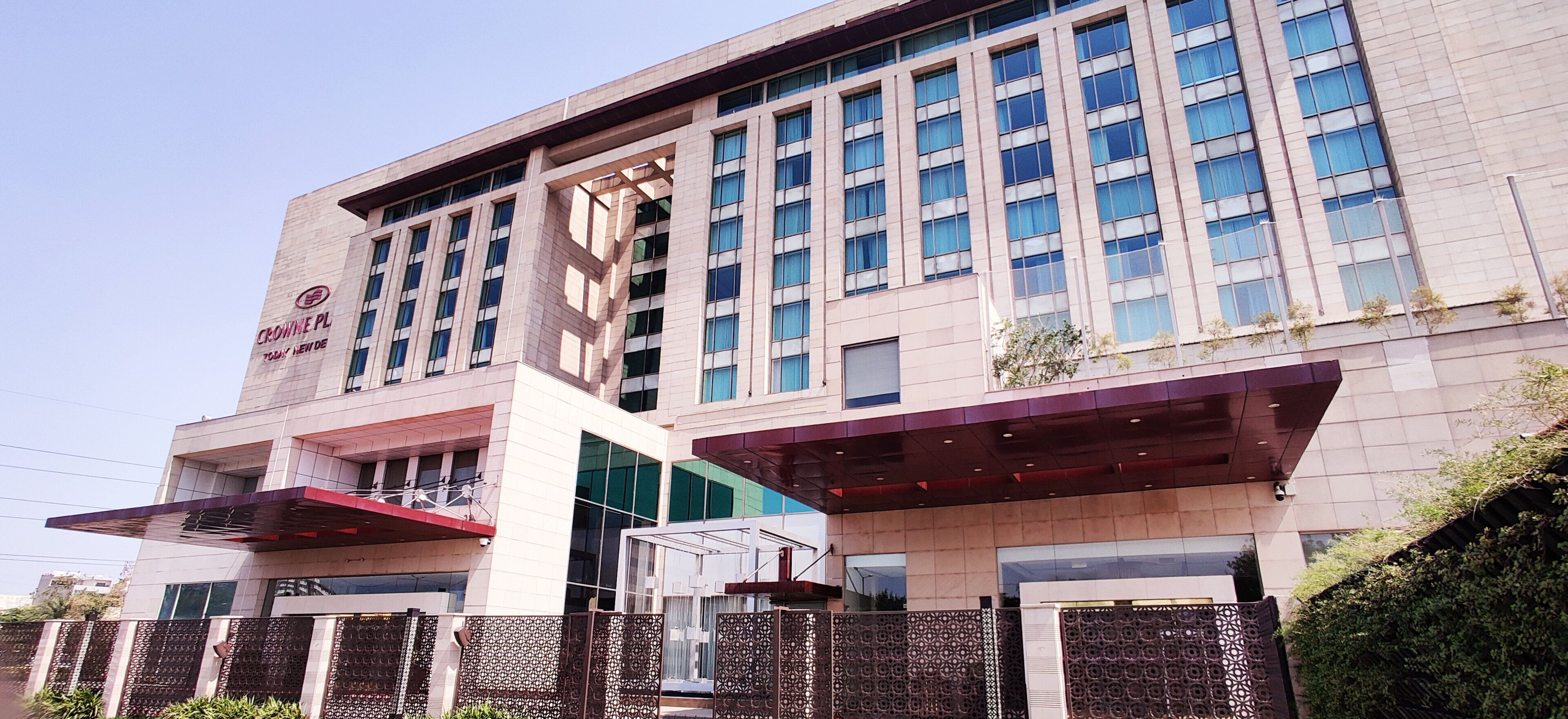 A modern building with a prominent sign reading 'CROWNE PL' and a large glass facade.