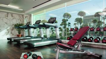 A gym with treadmills, dumbbells, and a bench press.