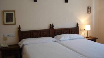 Una cama doble con cabecera de madera, dos mesitas de noche y una lámpara de pared.
