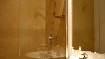 Un baño con ducha vidriada, lavamanos y espejo.