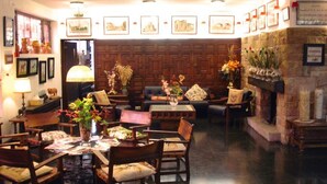 A cozy lobby with wooden furniture, a fireplace, and framed pictures on the walls. - Tierra De Campos (Osorno)