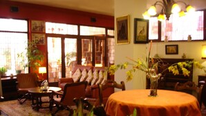 A cozy room with a round table covered in a red tablecloth, a sofa with patterned cushions, and a bookshelf. - Tierra De Campos (Osorno)