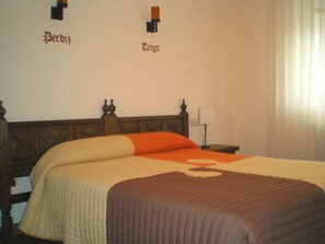 Ein Hotelzimmer mit einem großen Bett, einem Nachttisch, einer Lampe und einem Fenster mit Vorhängen.