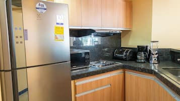 A kitchen with a stainless steel refrigerator, microwave, toaster, and blender on the counter.