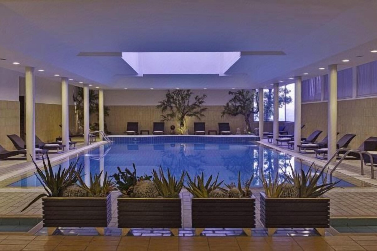 Una piscina interior con sillones de descanso y jardineras.