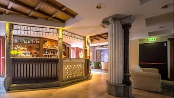 Zona de bar con techo de madera, una columna de piedra y un área de descanso con un sofá.