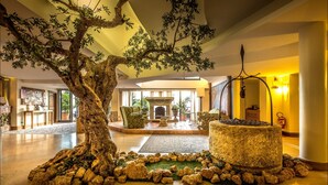 Un vestíbulo con un gran árbol artificial, una fuente de piedra y una chimenea.