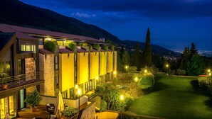 Un hotel de diseño moderno, con balcón y mobiliario exterior, y un césped cuidado.