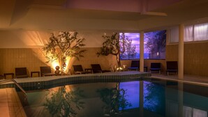 Una piscina interior con sillones de descanso y un árbol grande en el centro.