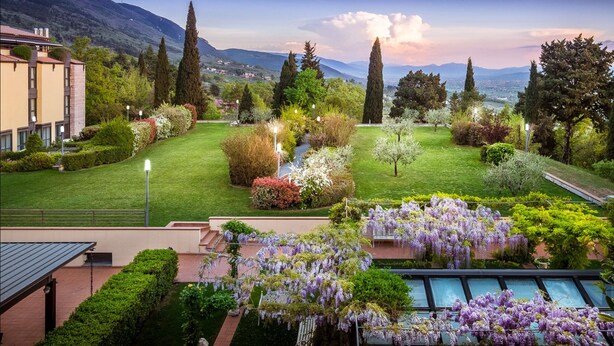 Un jardín ajardinado con piscina, césped impecable y vistas a montañas distantes.