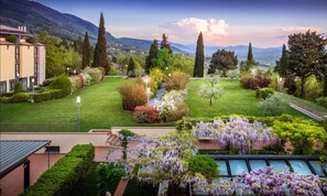 Um jardim ajardinado com piscina, gramados bem cuidados e vista para montanhas distantes.