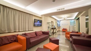 Una sala de estar moderna con un conjunto de sofás, un televisor y una araña.