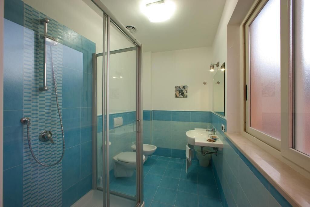 Uma casa de banho com cabine de chuveiro em vidro, sanita e lavatório.