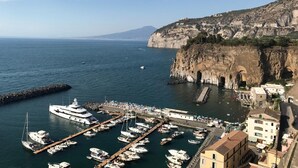 Un puerto deportivo con barcos amarrados, una costa rocosa y edificios a lo largo de la orilla.